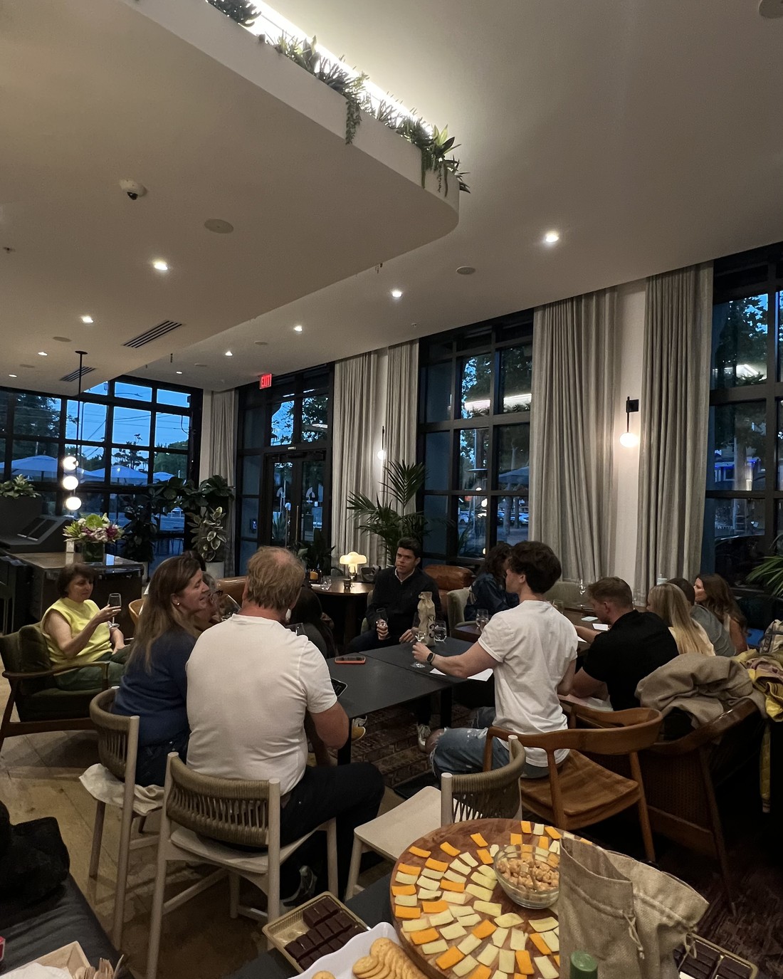 Guests seated across several tables at a private tasting, wine in hand.